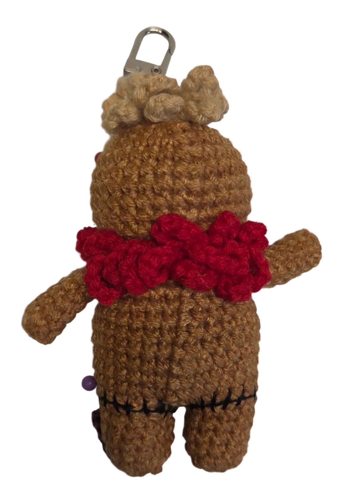The back of a crochet doll with a keychain atop its head. It is wearing a curly red collar.
