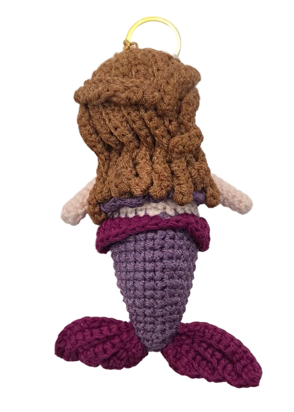 The back of a small crocheted mermaid keychain with brown hair, a purple tail, and a gold key ring, shown on a plain white surface.