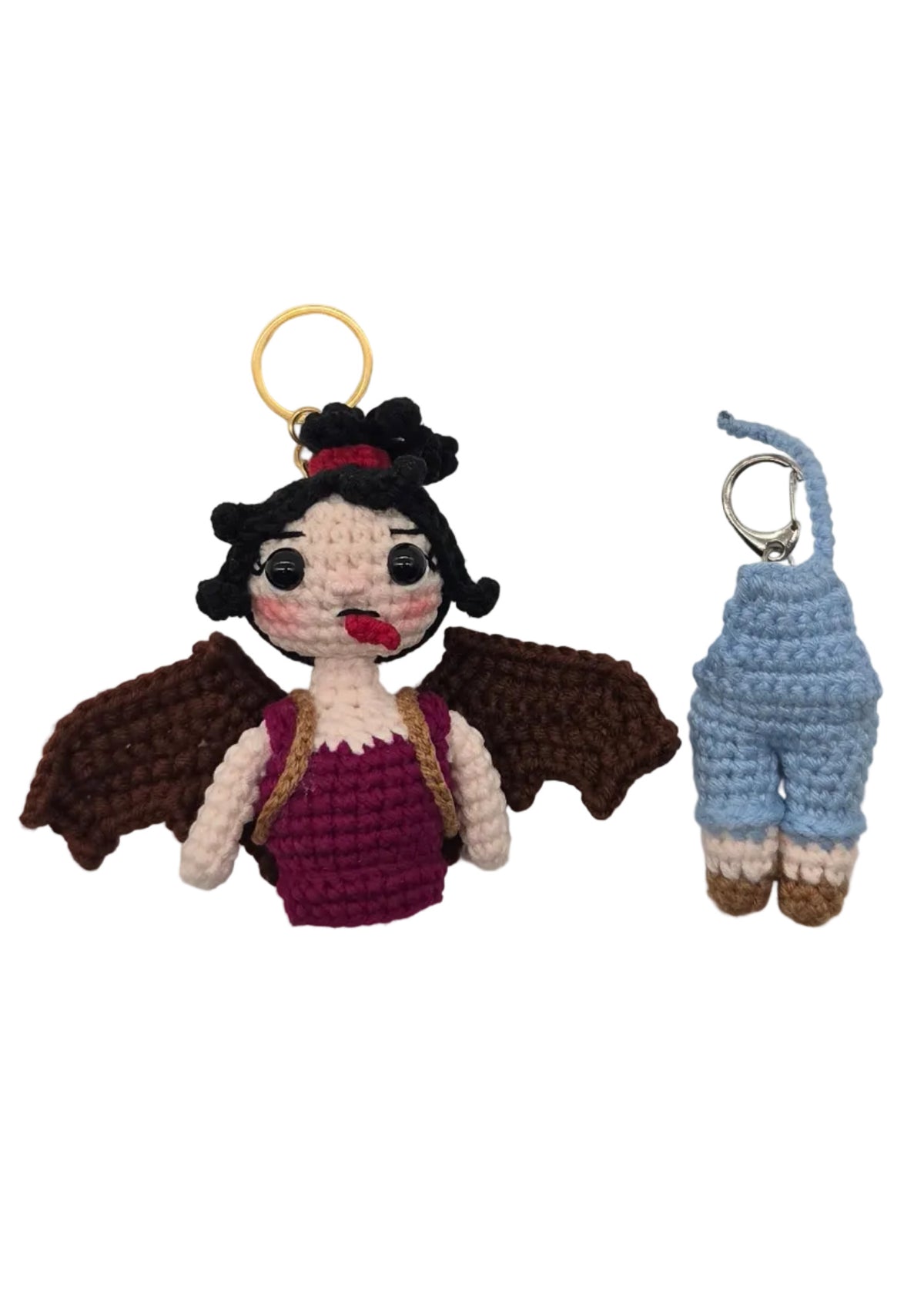 Two small crocheted keychains on a plain white background, one upper body half with a gold key ring and one lower body half with a silver key ring.
