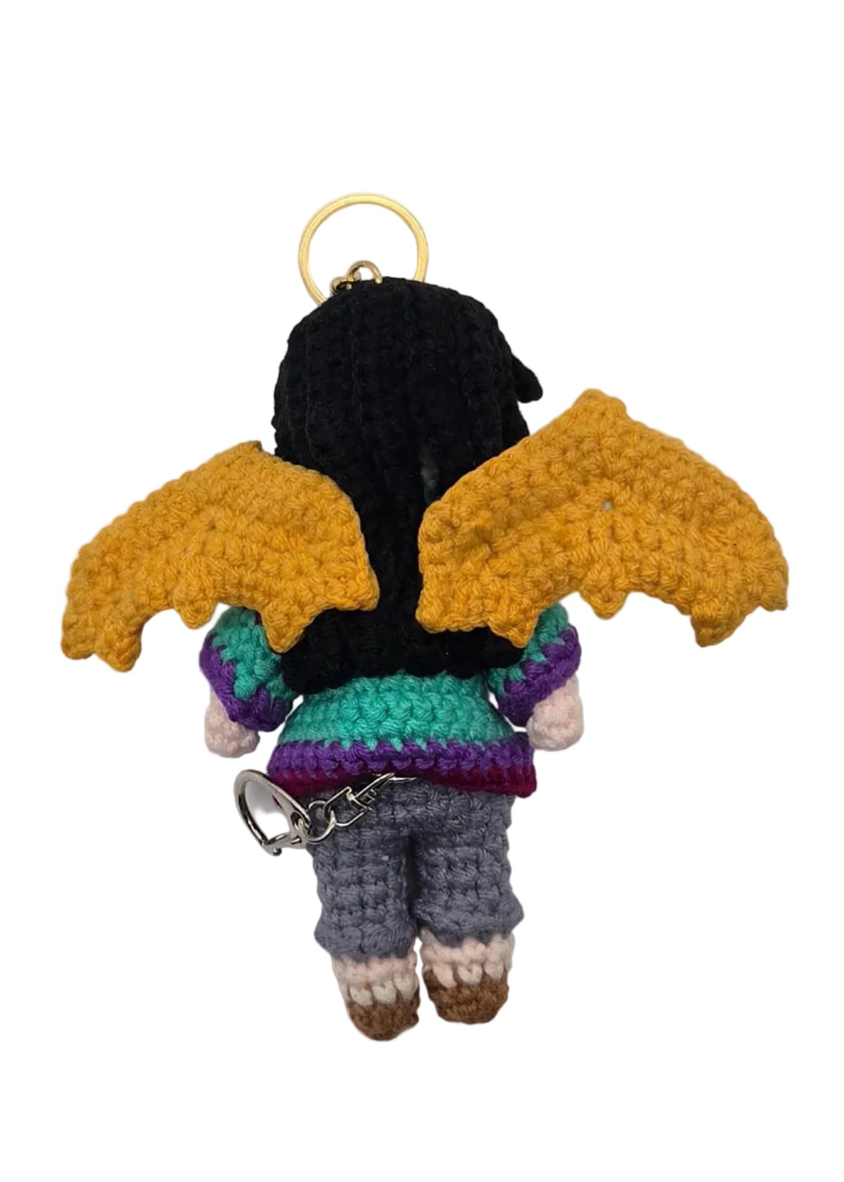 Back of a crocheted manananggal character keychain shown from the back, featuring a black hair, yellow wings, and a purple and teal striped sweater,  photographed against a white background.