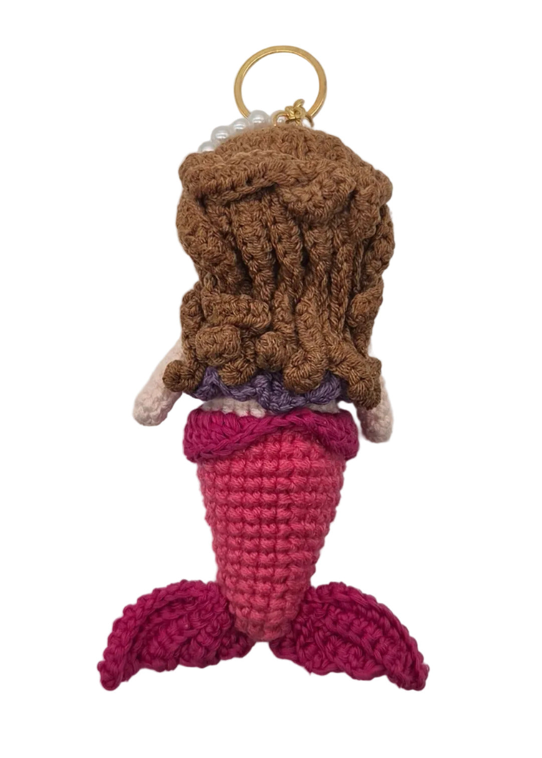 The back of a small crocheted mermaid keychain with brown hair, a pink tail, and a gold key ring, shown on a plain white surface.