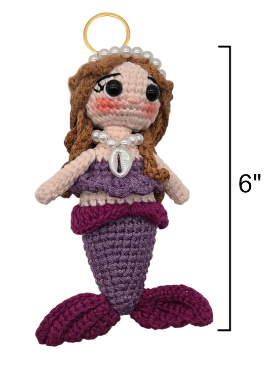 A crocheted sirena doll on a gold keychain, brown hair, a purple top, shell necklace, and purple tail, shown on a white background with a 6-inch height marker.