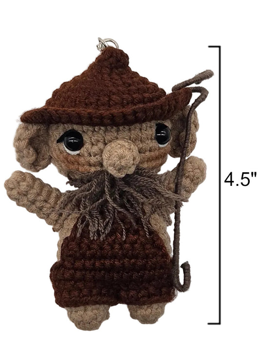 A handmade crocheted dwende with a brown cap, brown beard, and brown overalls, shown against a plain white background. A black measurement bracket on the right indicates a height of 4.5 inches.