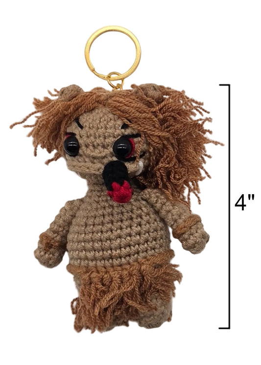 A crocheted doll keychain with messy brown yarn hair, a beige body, black bead eyes, a cigar, and a gold metal key ring. A black measurement bracket on the right indicates a height of 4 inches.