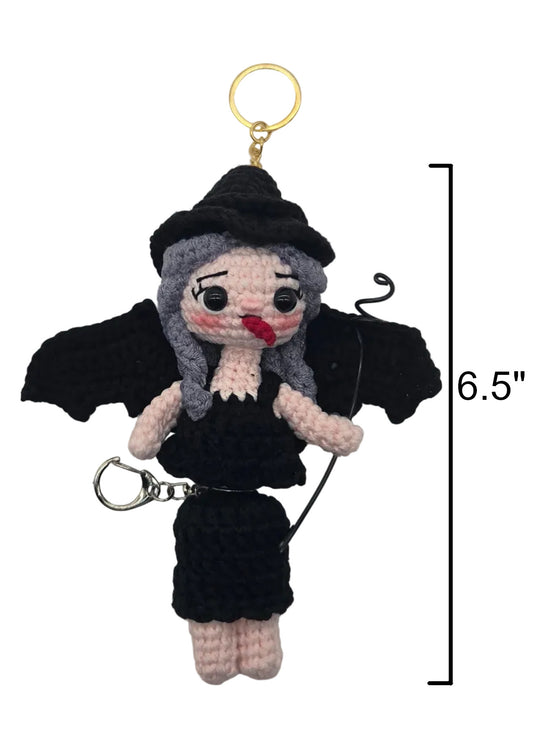 A crocheted manananggal doll keychain with black wings, a black hat, and a gold key ring, shown on a white background with a 6.5-inch height measurement marker.