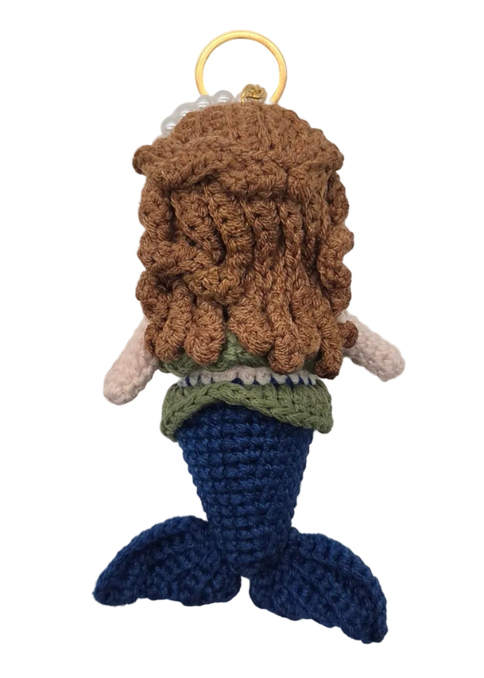The back of a small crocheted mermaid keychain with brown hair, a blue tail, and a gold key ring, shown on a plain white surface. 