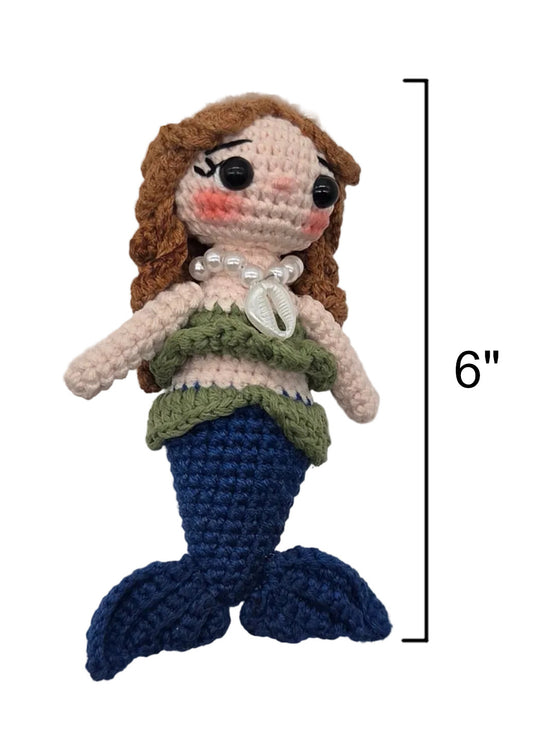 A crocheted sirena doll on a gold keychain, brown hair, a green top, shell necklace, and blue tail, shown on a white background with a 6-inch height marker.