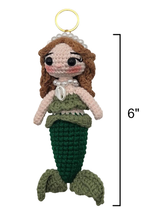 A crocheted sirena doll on a gold keychain, brown hair, a green top, shell necklace, and green tail, shown on a white background with a 6-inch height marker.