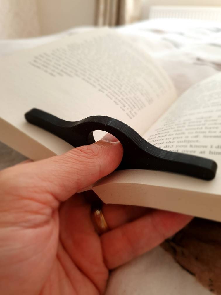Hand holding a black book holder over an open book